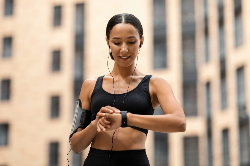 Sporty Young Woman Looking At Smartwatch, Tracking Fitness Activity During Training Outdoors